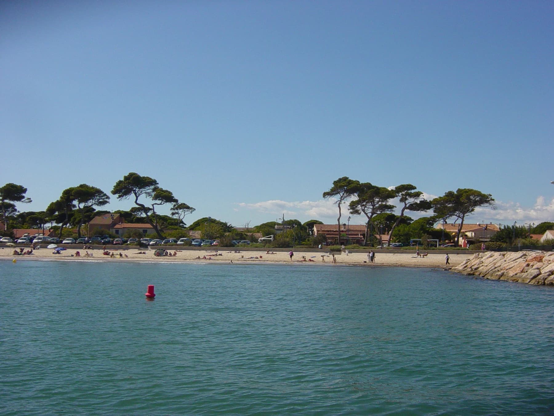 Plage de La Capte photographiée depuis la mer, avec des pins et des maisons en arrière-plan