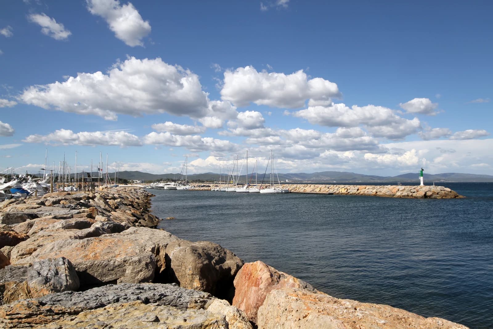 Entrée du Port d’Hyères, voiliers et digue sous un ciel nuageux