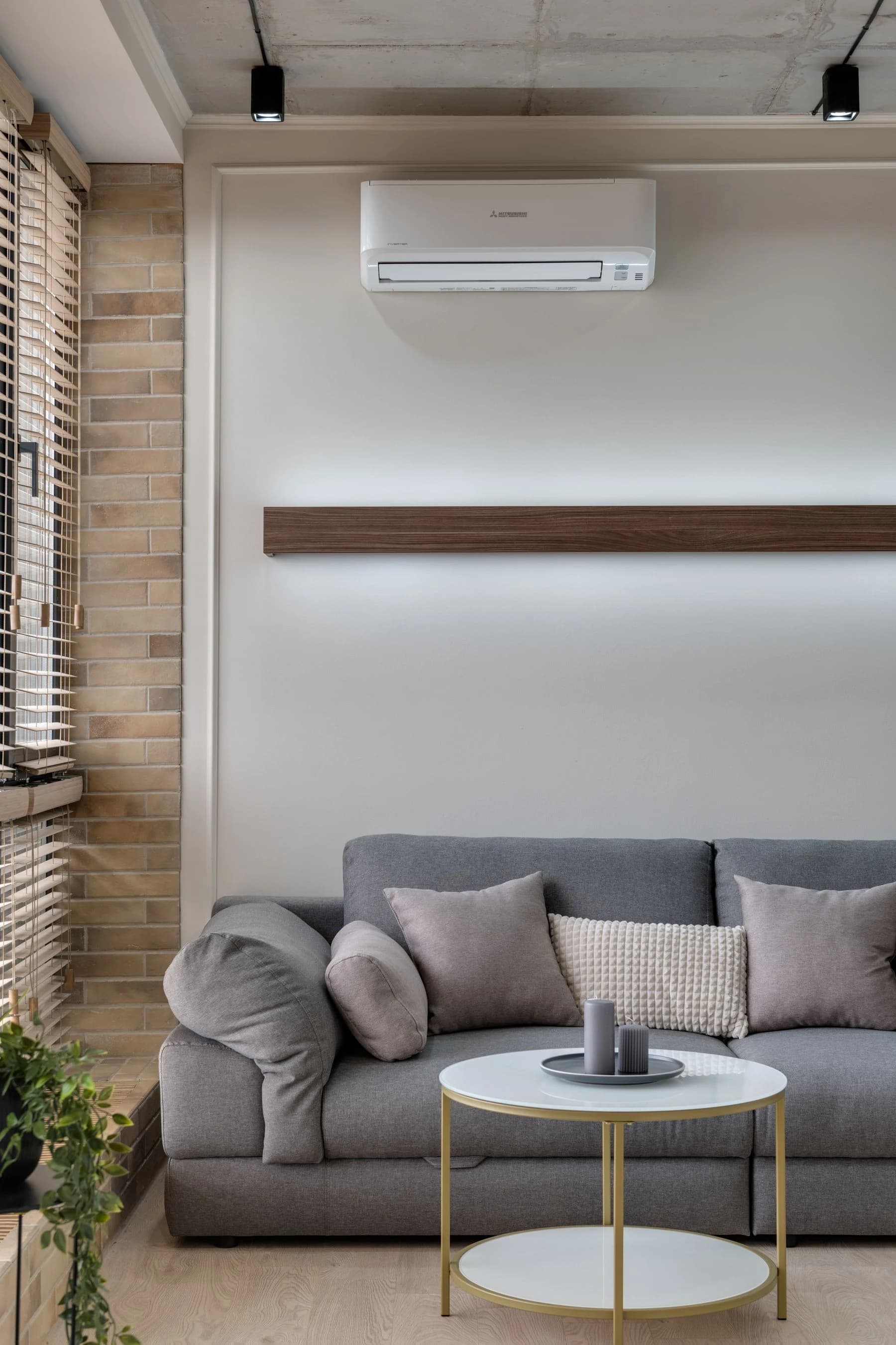 Climatisation murale blanche au-dessus d’un canapé, dans un intérieur aux tons naturels